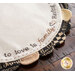 The edge of the Welcome Home Scalloped Table Topper on a dark brown table