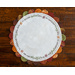 Round autumn themed scalloped table topper on a wood background