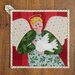 Top down view of the Better Not Pout Angel Pot Holder laid flat on a wood table