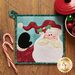 Square pot holder with applique Santa Claus on a wood table