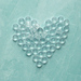 Beautiful clear beads in the shape of a heart on a turquoise table