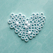 Beautiful white beads in the shape of a heart on a turquoise table