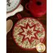 The cream La Rose Rouge folded star hot pad on a wood background
