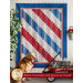 A beautiful red, white, and blue quilt hung from a wall with a small red wagon nearby