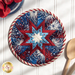Patriotic themed hot pad with fireworks laid flat on a wood table