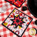 Red and white Peace, Love & BBQ Folded Star Squared Hot Pad on a red and white checkered table