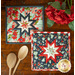 The two coordinating Folded Star Square Hot Pads made with Sunday Stroll fabrics on a wood table