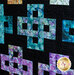 A close-up of a vibrant quilt featuring colorful geometric patterns on a black background.