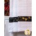Close up of waffle textured white towel with black and gold band.