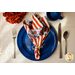 A patriotic cloth napkin made with Land That I Love fabrics resting on a blue plate on a table