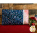 A patriotic pillowcase featuring bursting fireworks propped up against a wood wall 