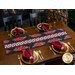 Christmas themed table runner featuring florals with white and black pinwheel center strip design on table set with matching gingham napkins.