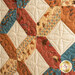 Quilt block featuring earth tones and fabrics printed with cowboy themed imagery.
