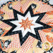 Round hot pad with central folded star, featuring white on peach polkadots and cartoon cats with jack-o-lanterns.