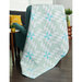 A beautiful light teal quilt draped over a chair in a home
