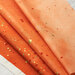 An orange ombre fabric with metallic accents.