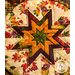 hot pad with autumn leaf motifs and central folded star design made with cream fabrics sitting on wood table next to pumpkins.