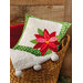 Small green and cream pillow with red poinsettia resting in a large basket.