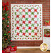 Christmas quilt hanging on brick wall featuring green and red stars on white background.