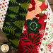 Hanging holiday stocking made from strips of Christmas themed fabric in red, green, and white.