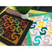 Two colorful Simply Snails Mini Quilts laid flat on a wood table