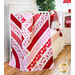 Quilt made of overlapping diagonal Valentine's Day themed strips of fabrics draped over furniture.