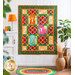 Multi colored quilt with jungle animals and geometric designs hanging on white paneled wall.