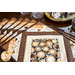 Coffee themed placemats made of brown, tan, and cream fabrics with coffee cups in the center surrounded by strips of fabric in a diamond shape.