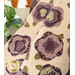 Cream quilt with flowers made of layered purple and green fabric draped over furniture.