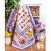 Quilt featuring multicolored watercolor florals on white with purple borders draped over furniture.