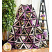 Purple and white quilt with triangle geometric design and floral prints draped over furniture.
