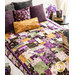 Quilt with patchwork design made of purple, yellow, teal, and black fabrics featuring florals, fish, and butterflies on bed with matching pillows.