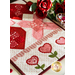 The table runner from another angle, staged with red roses and showing fabric and stitching details.