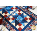 Red, white, and blue table runner made of patriotic fabric prints and geometric piecing.