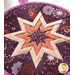 Round hot pad with central folded star design made of purple floral fabrics.