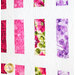 Quilt of squares and rectangles made of pink, purple, and green floral fabrics on white background.