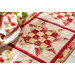 Table runner made of pink and red fabrics with geometric square and triangle designs in blocks.