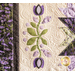 Close-up of a quilt featuring lavender and floral designs in purple and green tones on a cream background.