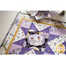 Table runner with geometric design with white and purple lavender and bee themed fabrics on table set with matching napkins.