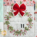 Close up of Patchwork quilt featuring Christmas themed motifs including a wreath and bow.
