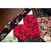 Table runner with interlocking heart design featuring rose themed prints in red, black, and green.