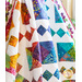 White quilt with multicolor floral and geometric designs draped over furniture.