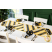 Table runner made of diagonal strips of bee themed fabrics in yellow, black, and white.