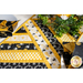 Table runner made of diagonal strips of bee themed fabrics in yellow, black, and white.