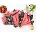 Top down image of cloth napkins arranged in a fan with a bowl of strawberries and vase of daisies nearby