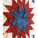 A close-up of a star-pattern quilt featuring red, white, and blue fabrics in a geometric design.