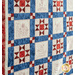 30 block quilt made of alternating blocks of geometric piecing and summer themed embroidery in red, white, and blue fabrics.