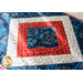Table runner with central diamond design and angled strips at the ends made of patriotic printed fabrics.
