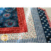 Table runner with central diamond design and angled strips at the ends made of patriotic printed fabrics.