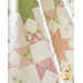 A quilt with geometric square and triangle designs made of pastel color fabrics on white draped over furniture.